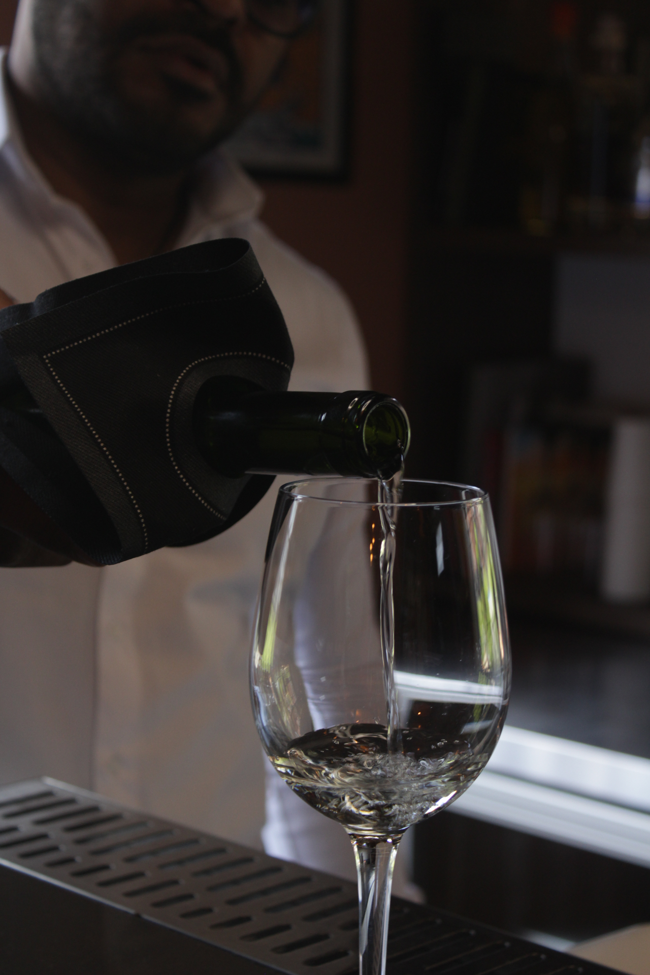 Botellero Roll Drap negro envolviendo una botella de vino mientras se sirve una copa